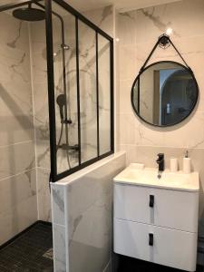 ein weißes Badezimmer mit einem Waschbecken und einem Spiegel in der Unterkunft Le charme et l’original in Ailly-le-Haut-Clocher