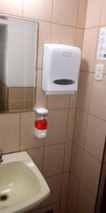 a bathroom with a sink and a soap dispenser on the wall at Hostal Residencial Mochica in Lima