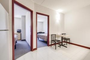 a room with a bed and a table and a mirror at Residence & Conference Centre - Welland in Welland