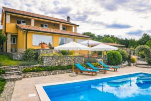 una piscina con sillas y sombrillas frente a una casa en *****Pool house with beautiful seaview,big garden and old tavern*****, en Rijeka