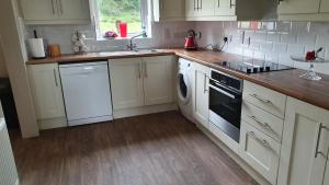 a kitchen with white cabinets and a sink and a dishwasher at Bridgeburn Apartment in Letterkenny