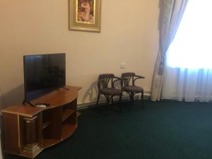 un soggiorno con TV e 2 sedie di Budynok Pyschevycha a Oleksandriya