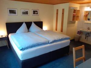 Schlafzimmer mit einem Bett mit blauer Bettwäsche und einem Waschbecken in der Unterkunft Gästehaus Sahler in Gaschurn