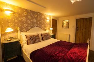 um quarto com uma cama com uma parede floral em Hollybush Inn em Greenhaugh