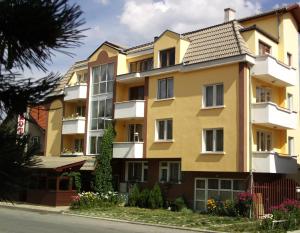 a yellow building with white balconies on a street at Guest House Zodiac in Samokov