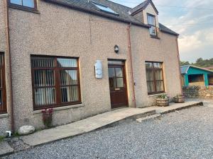 a brick house with a door and a driveway at The Old Dairy in Lairg