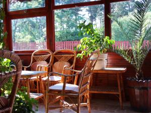 un patio con sillas, mesas y ventanas en Guest House Zodiac, en Samokov