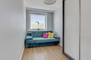 salon z niebieską kanapą i oknem w obiekcie Comfort Apartments Wyspiańskiego w mieście Gdynia
