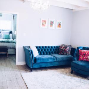 a living room with a blue couch and two chairs at Sunny Brae Cottages in Tauranga