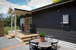 a patio with a table and chairs and a building at Sunny Brae Cottages in Tauranga