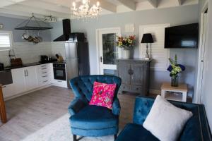 a living room with a blue chair with a pink pillow at Sunny Brae Cottages in Tauranga