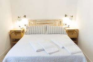 uma cama branca com dois candeeiros em duas mesas de cabeceira em La Antigua Fonda em Hervás