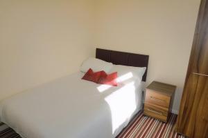 a bedroom with a white bed with two red pillows at The Harvest 2 in Canterbury