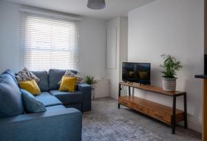 a living room with a blue couch and a tv at Eastside View Apartment in Whitby