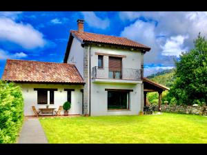 a white house with a balcony and a grass yard at Laurel de Gulpiyuri de Llanes in Villahormes