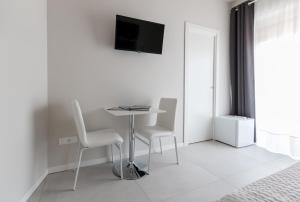 a white room with a table and two chairs and a tv at PhotoRooms B&B in Siracusa