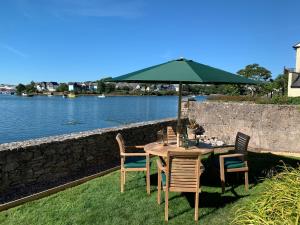 a table with chairs and an umbrella next to the water at Clover Cottage in Plymouth