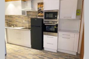 a kitchen with white cabinets and a black refrigerator at Calme dans Maison de village 60M2 super confort in Digne-les-Bains