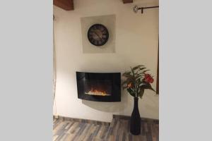 a fireplace in a wall with a clock and a vase of flowers at Calme dans Maison de village 60M2 super confort in Digne-les-Bains