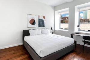 a white bedroom with a bed and a desk and window at Kislak 405 Luxurious 1BR Retreat Above the City in Newark