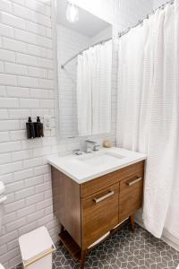 Baño blanco con lavabo y espejo en Kislak 407 Stunning 2BR Corner Apt Retreat Above the City, en Newark