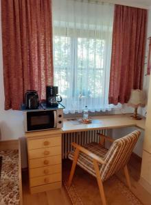 eine Küche mit einem Schreibtisch, einer Mikrowelle und einem Stuhl in der Unterkunft Appartemant Steineberg in Immenstadt im Allgäu