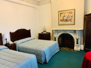 a bedroom with two beds and a fireplace at Avonmore On The Park Boutique Hotel in Sydney