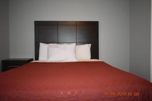 un letto con coperta rossa e cuscini bianchi di Time Travellers Motel a Petawawa