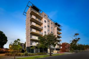 un edificio de apartamentos alto con un árbol delante en Quest on Rheola, en Perth