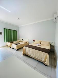 2 łóżka w pokoju z zielonymi zasłonami w obiekcie Hotel Pousada Marra w mieście Catalão
