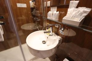 a bathroom with a white sink and a glass wall at Hotel Kanade Kanku Kaizuka in Kaizuka