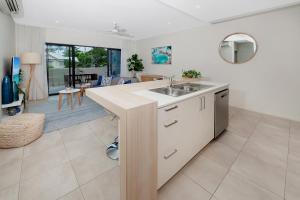 eine Küche mit einem Waschbecken und ein Wohnzimmer in der Unterkunft Apartment Close to the City Life on Lake 3 in Cairns North