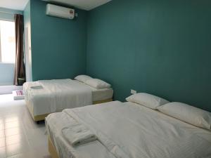a bedroom with two beds and a blue wall at Qeyjan Hotel in Pasir Puteh