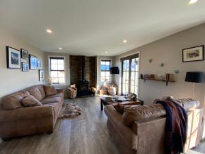 een woonkamer met 2 banken en een open haard bij Pedalfish Cottage in Twizel