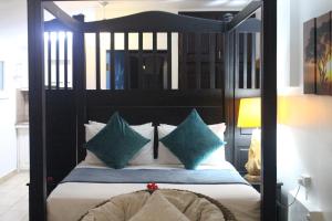 um quarto com uma cama de dossel preta com almofadas verdes em Stephna Residence em Anse Boileau