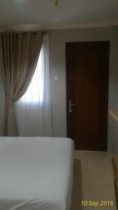 Omnea Hotel - Syariah في بنجكولو: غرفة نوم بسرير ونافذة وباب