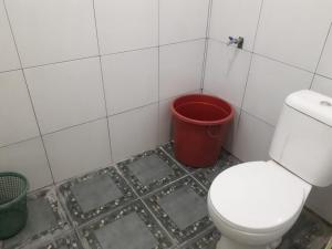 a bathroom with a white toilet and a red bucket at Pesona Wisata Alam Ciparay Endah in Bogor