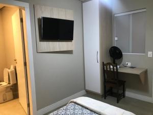 a room with a desk and a television on a wall at Piemont Hotel in Curitiba