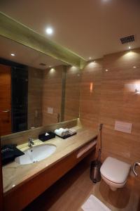 een badkamer met een wastafel, een toilet en een spiegel bij Best Western Plus Tejvivaan in Visakhapatnam