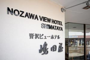 Nozawa View Hotel Shimataya في نوزاوا أونسن: لافته لفندق مطل على نوزاوا من جهة مبنى