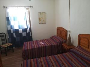 a bedroom with two beds and a chair and a window at PENSION LA FUENTE in Abrucena