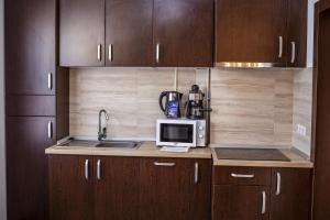 a kitchen with wooden cabinets and a microwave at Apartament Family Rivulus 10 in Baia Mare