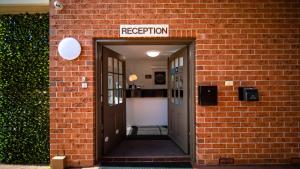 an entrance to a brick building with a sign that reads reception at Hamilton's Queanbeyan Motel in Queanbeyan