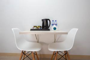 a table with three white chairs and a coffee maker on it at Urban Express HomTel - Serpong in Banten