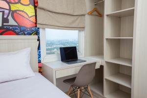a bedroom with a bed and a desk with a laptop at Urban Express HomTel - Serpong in Banten