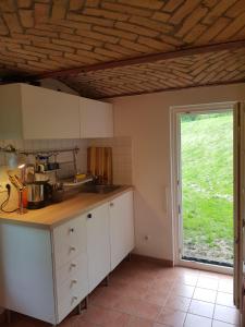 eine Küche mit weißen Schränken und einem großen Fenster in der Unterkunft Niedliches kleines Ferienhäuschen auf Rügen nahe Stralsund in Altefähr