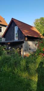 una casa con techo rojo y hierba verde en Niedliches-kleines-Ferienhaeuschen-auf-Ruegen-nahe-Stralsund, en Altefähr