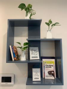 a shelf with books and a plant on it at A Cosy Apartment in Vinhomes Green Bay Ha Noi in Hanoi