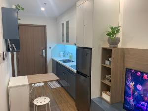a kitchen with a refrigerator and a table and stool at A Cosy Apartment in Vinhomes Green Bay Ha Noi in Hanoi