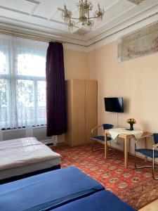 a bedroom with two beds and a desk and a tv at Hotel Gunia in Berlin